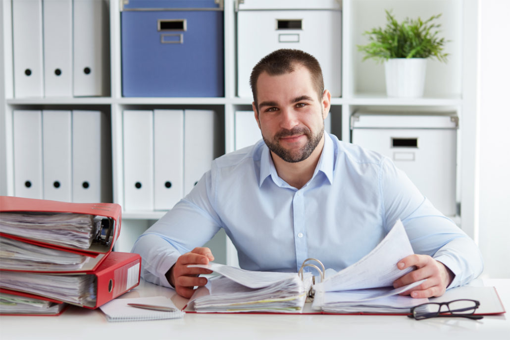 Young businessman calculates taxes at desk in office